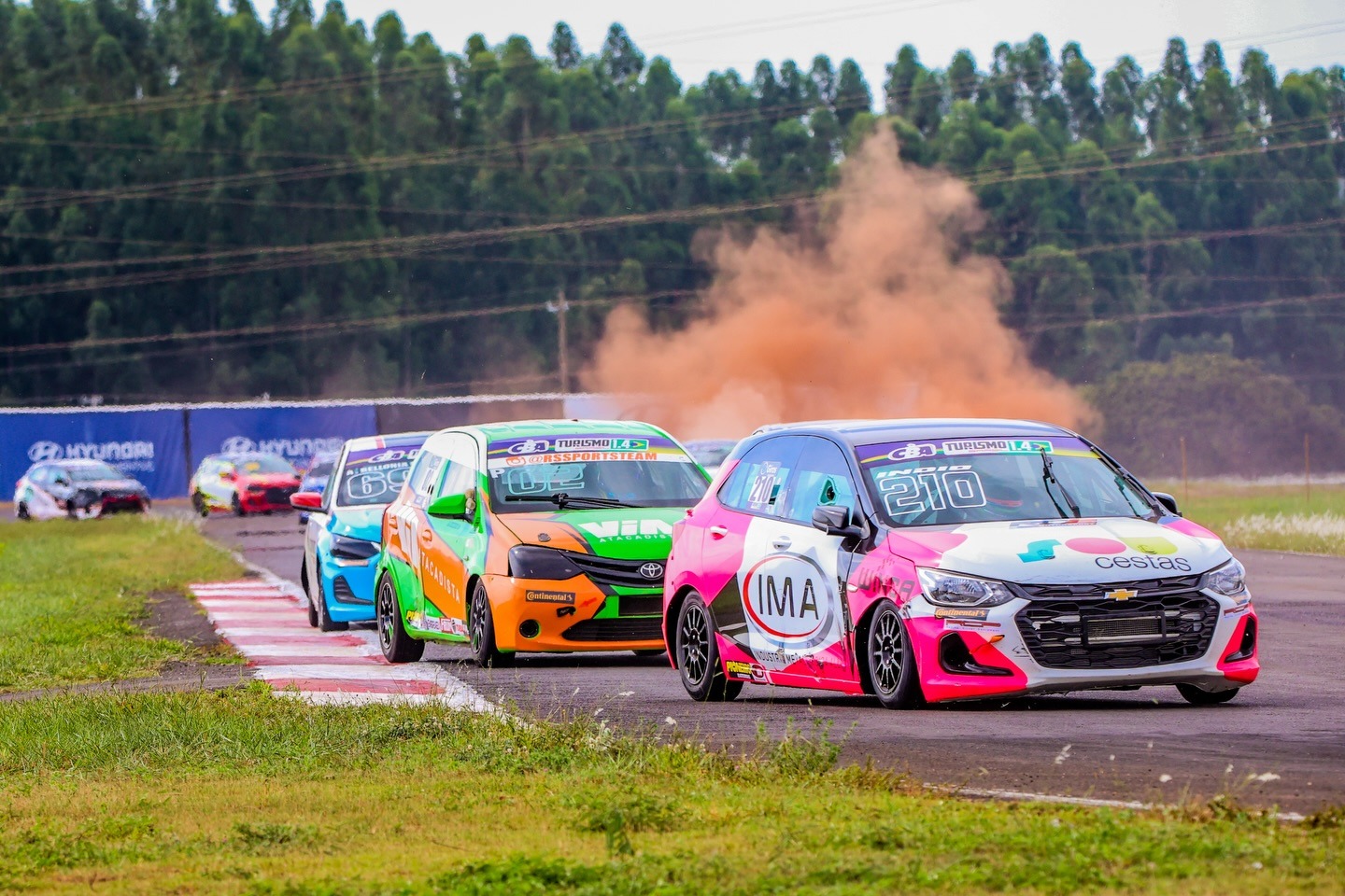 Carros da Copa em pista com fumaça laranja